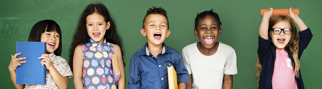 Five children standing together smiling and holding books. 