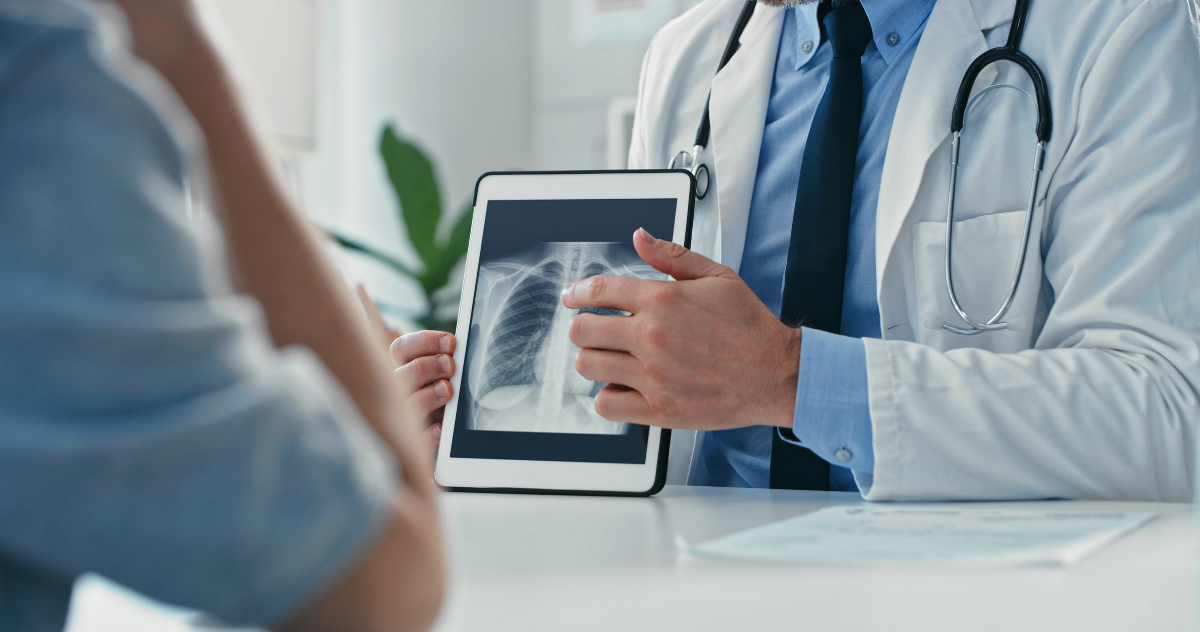 Cropped shot of an unrecognisable doctor sitting with his patient and showing her x-rays on a digital tablet 