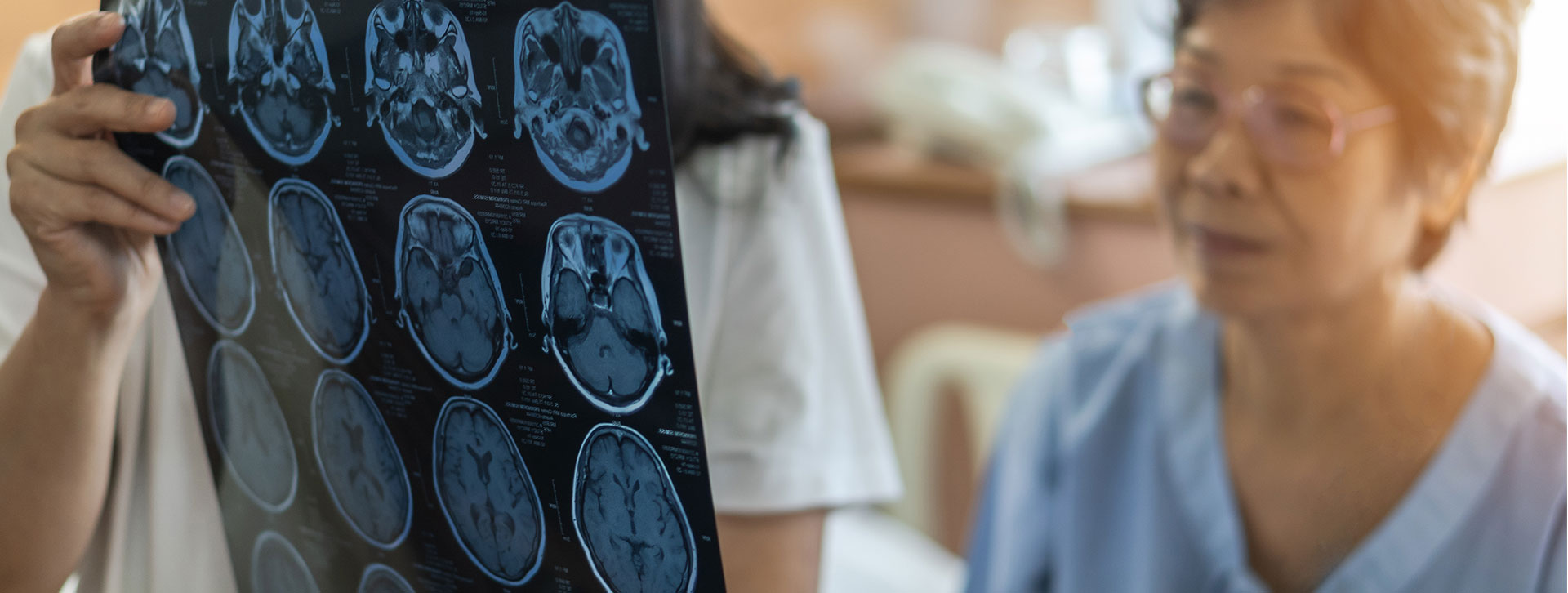 Medical doctor and patient looking at Magnetic Resonance Imaging (MRI) film of brain. 