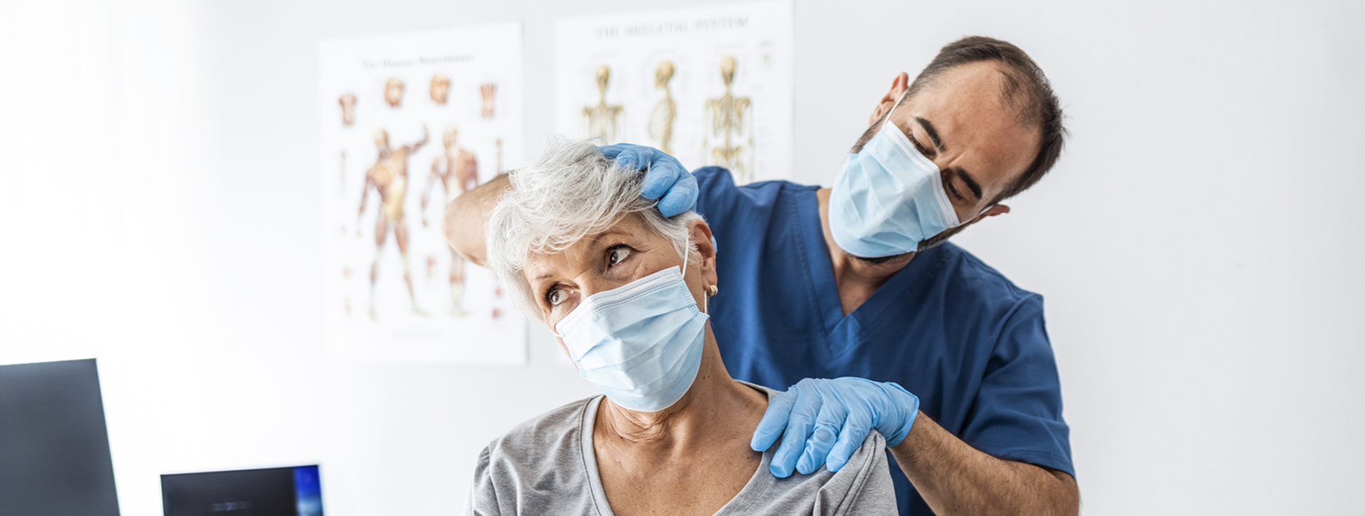 Male doctor examining an older female patient's neck. 