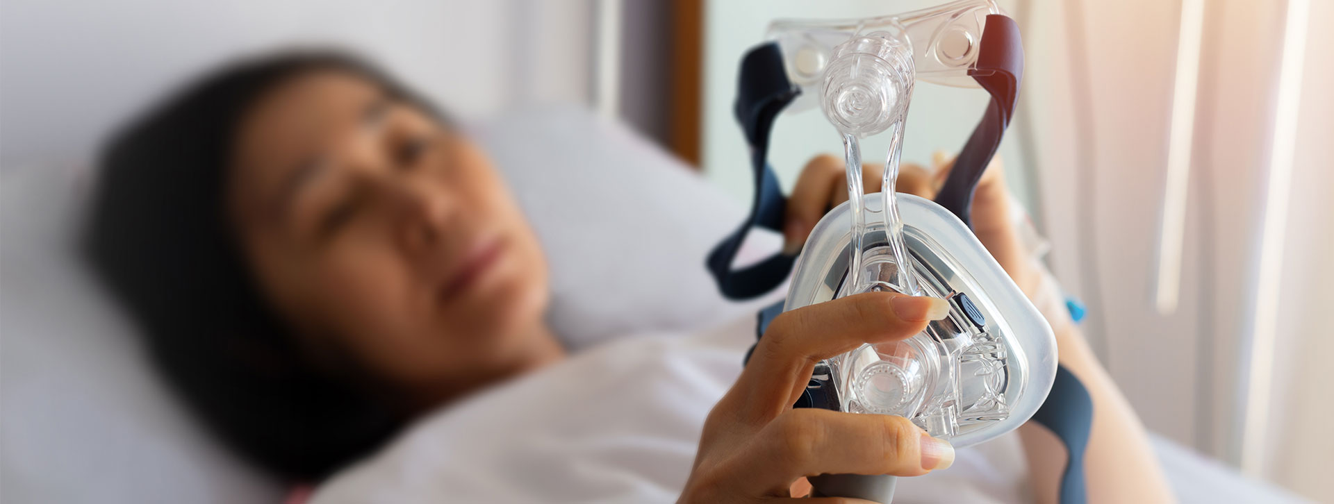 Senior patient woman hands holding Cpap mask lying in hospital room.