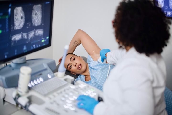 Woman receiving a breast cancer screening and a doctor looking over the results.