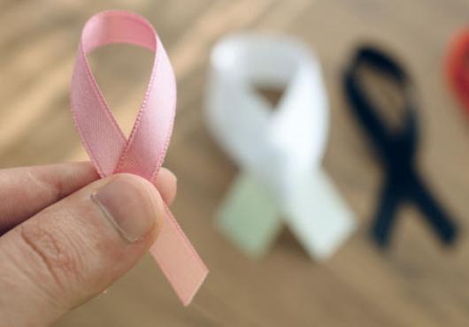 a hand holding a cancer support ribbon