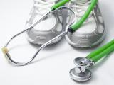 A lime green stethoscope laid over a pair of athletic sneakers.