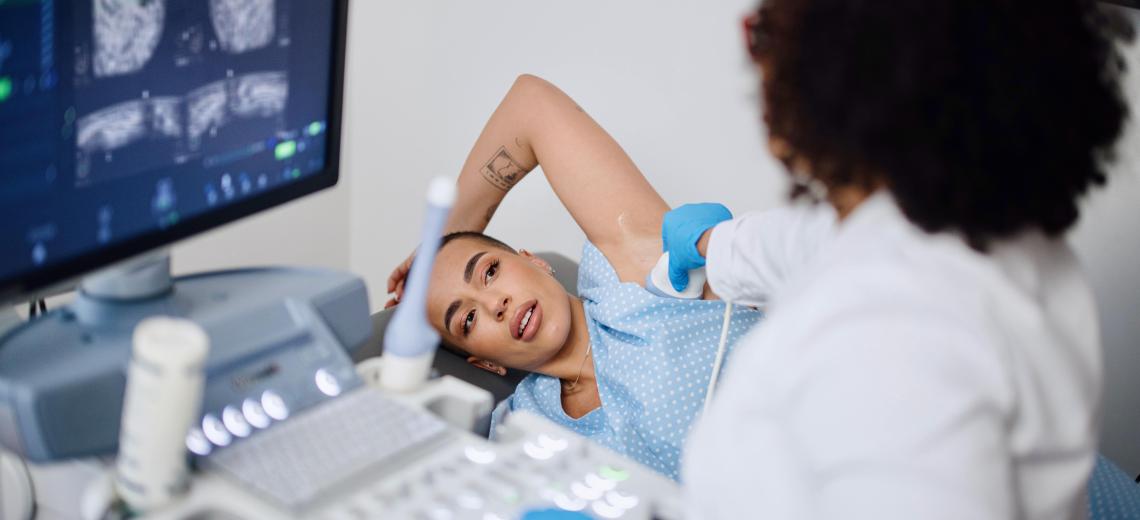 Woman receiving a breast cancer screening and a doctor looking over the results.