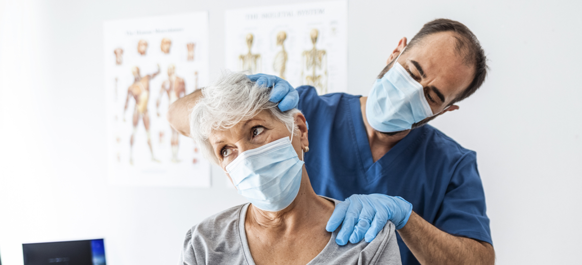 Male doctor examining an older female patient's neck.