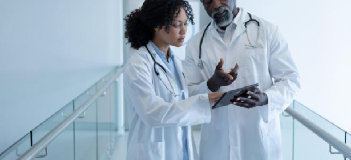 Two doctors standing in white coats looking at a tablet.