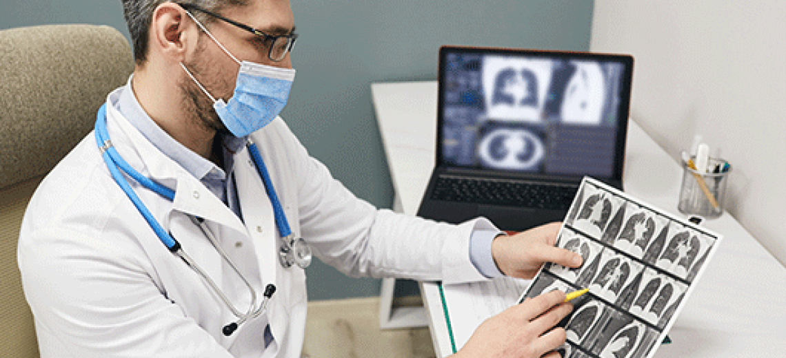 Doctor wearing a protective face mask analyzes results of a patient's lungs CT scan at a medical clinic